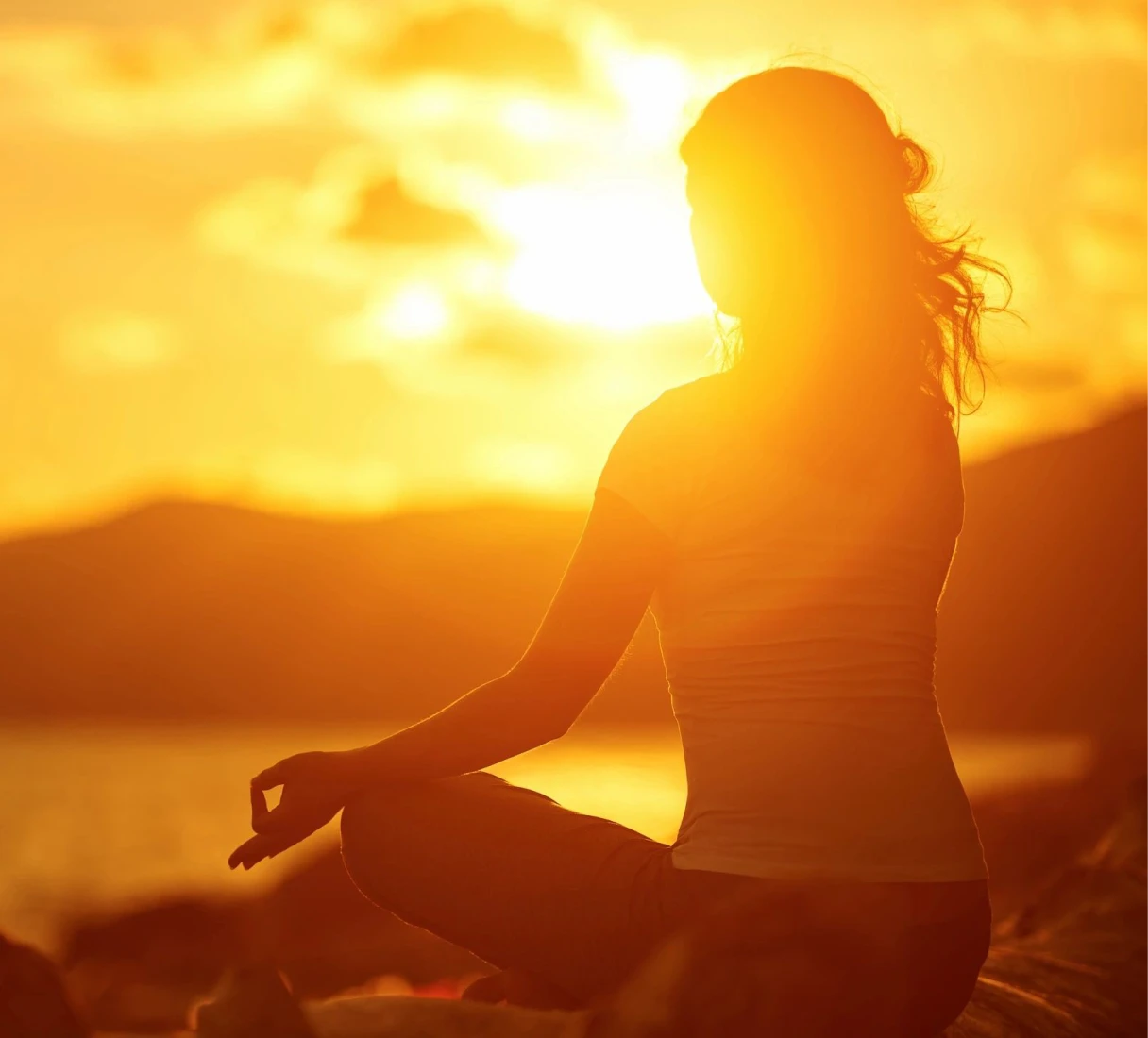 Person meditating at sunset